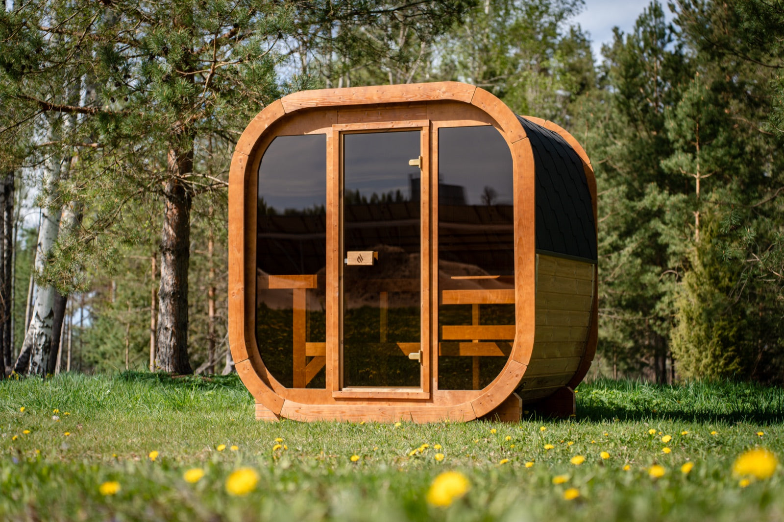Max Traditional Sauna 2.0 with its full glass front, among pines and birches